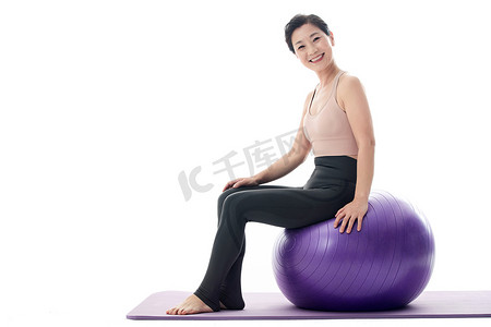 中年女性运动摄影照片_快乐的中年女性坐在瑜伽球上