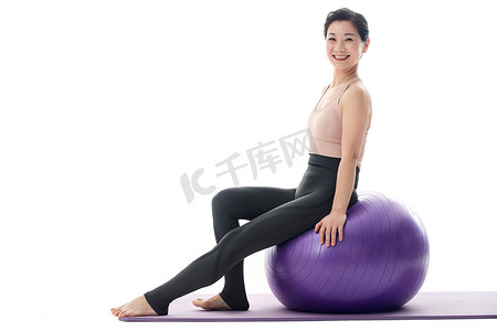 快乐的中年女性坐在瑜伽球上
