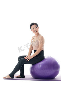 快乐的中年女性坐在瑜伽球上