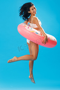 度假圈摄影照片_比基尼美女套着游泳圈跳跃