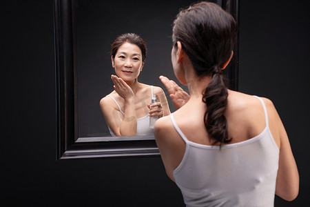中年女人对着镜子做面部护理