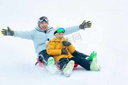 男人滑雪摄影照片_快乐父子坐着雪上滑板滑雪