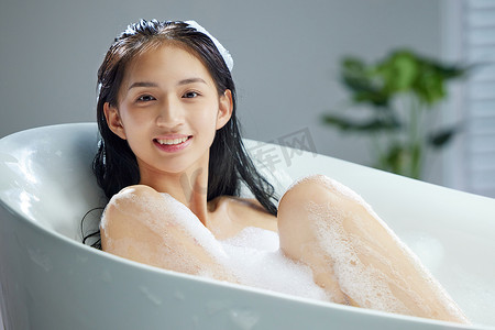 快乐的年轻女人洗泡泡浴