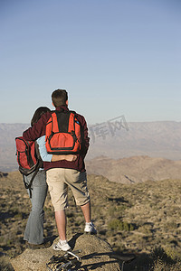 两人站在岩石上背对背欣赏景色