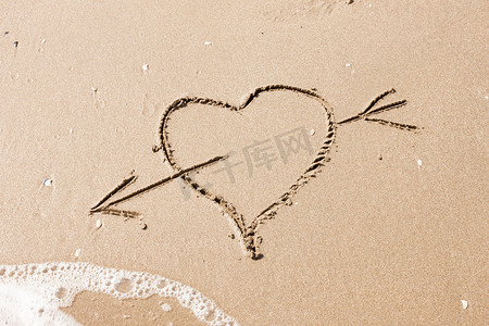 沙子上写着箭头的心