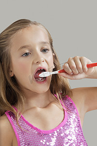 灰色背景下刷牙的年轻女孩