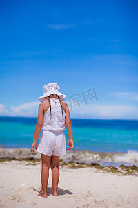 可爱的小女孩独自看着白色沙滩上的大海