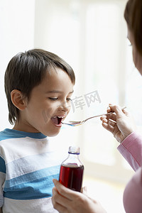 母亲在家给儿子止咳糖浆