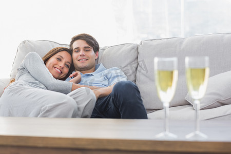 一对漂亮的夫妇躺在沙发上，端着香槟杯