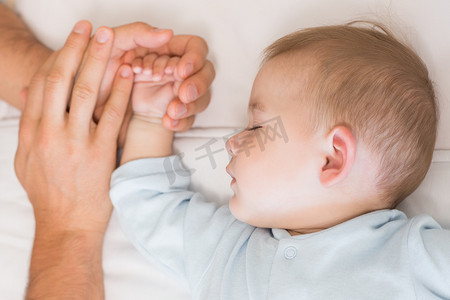 促销家装首页摄影照片_父母在婴儿床里牵着小儿子的手