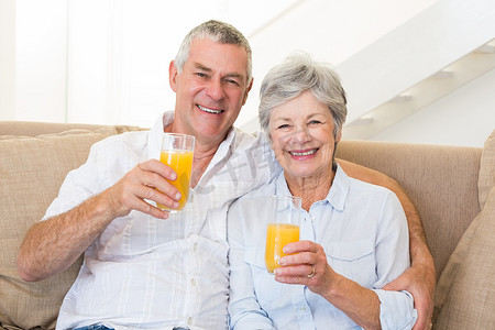 年长夫妇坐在沙发上喝橙汁