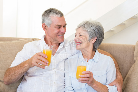 年长夫妇坐在沙发上喝橙汁
