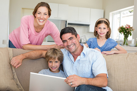 微笑的家庭在客厅里使用笔记本电脑