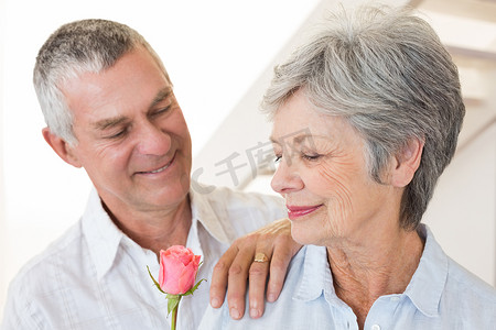 老人向他的伴侣献上一朵玫瑰