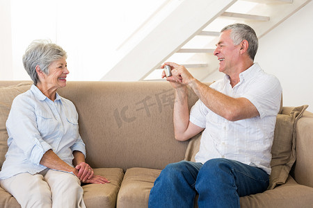 退休男子在沙发上为他的伴侣拍照