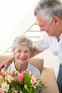 老人给他的伴侣一束鲜花，对着镜头微笑