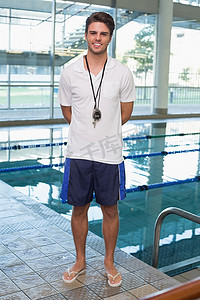 站在泳池边的游泳教练对着镜头微笑
