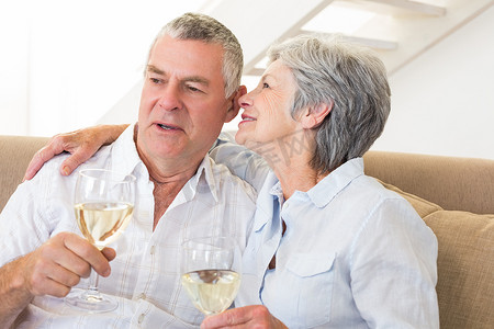 坐在沙发上喝白葡萄酒的年长夫妇