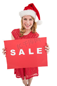 戴着圣诞帽的漂亮金发女郎拿着一张红色的促销海报
