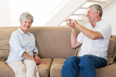 退休男子在沙发上为他的伴侣拍照