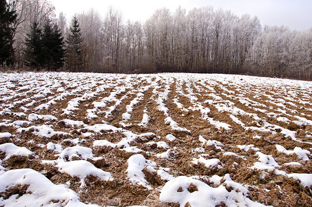 犁过的冬季农田田野覆盖着白雪