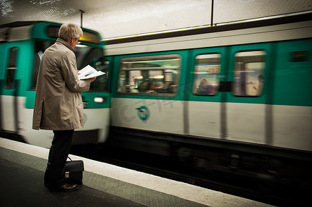 一个男人在地铁里等地铁时看报纸