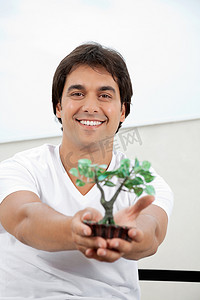 植物计划摄影照片_拿着人造植物的人