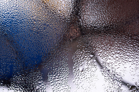 模糊窗户背景摄影照片_玻璃窗上的水滴紧靠着模糊的背景。