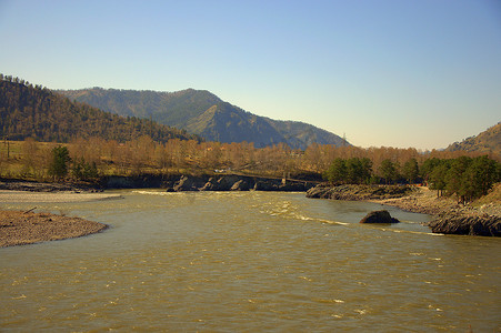 卡通大山背景摄影照片_湍急的卡吞河沿着阿尔泰山脚下流淌着碧绿的海水。