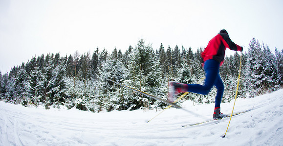 年轻人在多雪的森林小径上越野滑雪