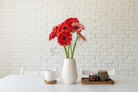 简约格调摄影照片_厨房桌上白色花瓶中明亮的非洲菊雏菊，简约风格