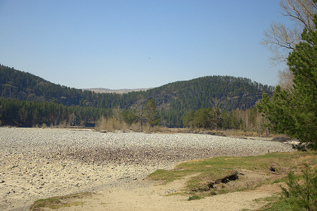 卡吞河的大河岸上铺满了圆石，背景是高山。