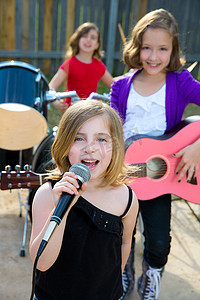 儿童乐队摄影照片_儿童歌手女孩在后院唱歌演奏现场乐队