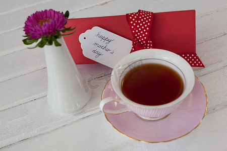 木表面上的红茶、花瓶和愉快的母亲节卡片