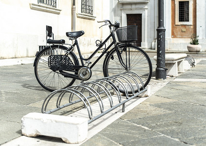 在意大利街道上的自行车架上安装的黑色自行车。
