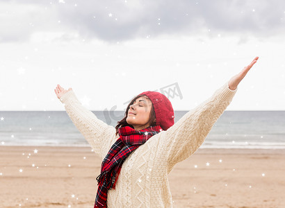 穿着保暖衣服的妇女在海滩上伸展双臂的合成图像