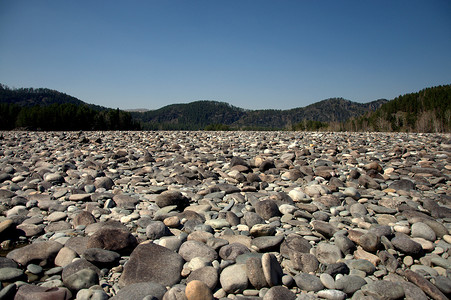 卡吞河的大河岸上铺满了圆石，背景是高山。