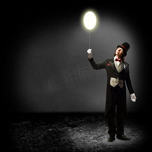 魔术师摄影照片_拿着发光气球的魔术师
