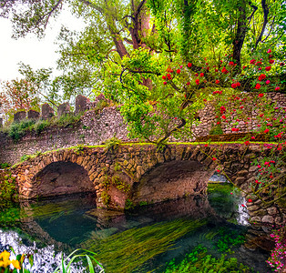 伊甸园色彩缤纷的花园中的中世纪石桥，玫瑰和河流充满活力