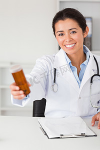 美丽的微笑医生坐着拿着一盒药