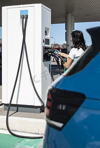 女人在加油站充电电动汽车。