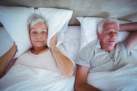 妻子用枕头堵住耳朵，丈夫在床上打呼噜