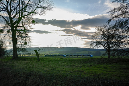 在绿色风景和多云天空中间的一辆移动的现代地方火车