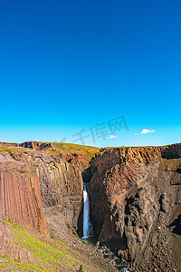 美丽而高大的冰岛瀑布 Hengifoss 和通往它的远足小径，冰岛，夏天，阳光明媚的日子，蓝天