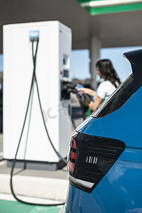 自动充电摄影照片_女人在加油站充电电动汽车。