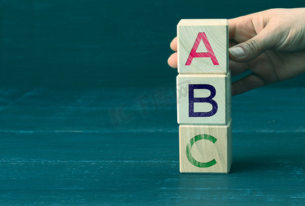 手拿着带有字母 A、B、C 的木制立方体。学前教育的概念。