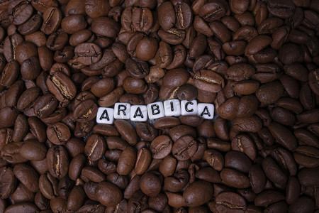 靠近用白色小方块写的 ARABICA 字样的新鲜烘焙咖啡豆的特写。