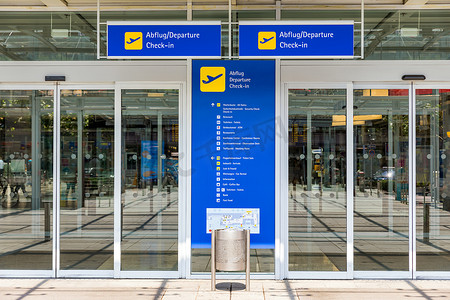 机场航站楼大门入口和自动玻璃门，带有德语和英语信息文本。
