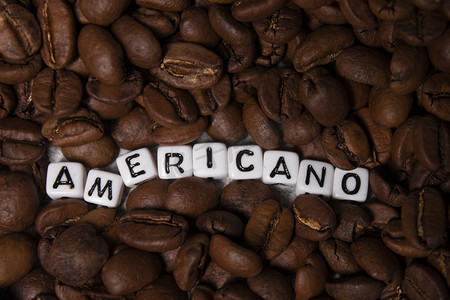 靠近用白色小方块写的 AMERICANO 字样的新鲜烘焙咖啡豆的特写。