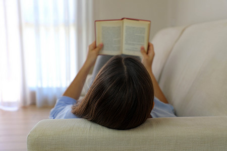 在家里放松的说谎的女人看书的特写。